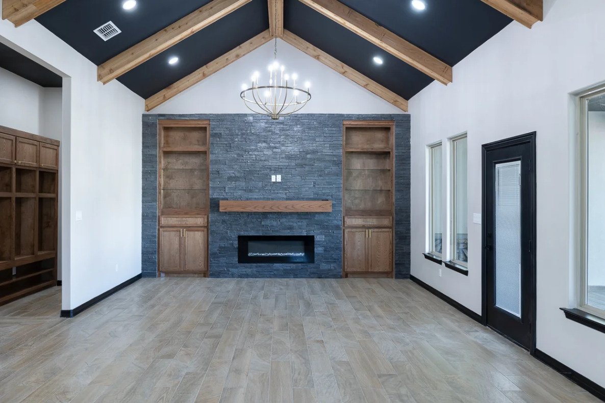 Large room with wooden floors and a fireplace, showcasing entertainment wall ideas for contemporary Texas homes. Entertainment Wall by Villanueva Construction