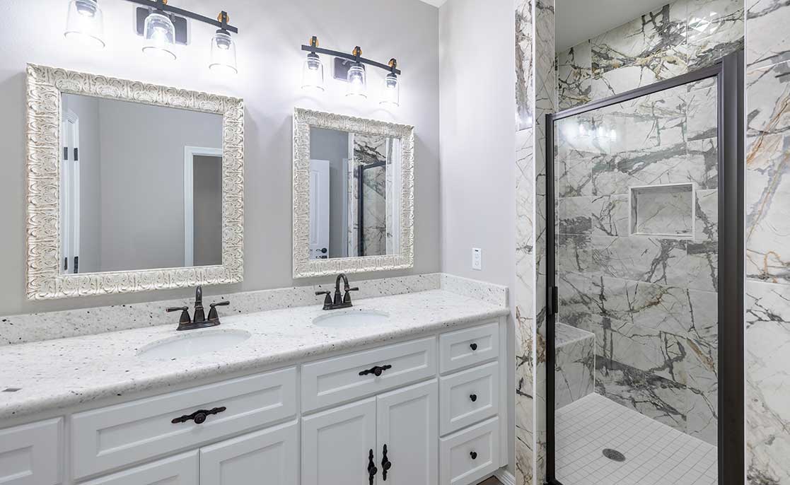 A modern bathroom featuring marble countertops and white cabinets, designed in a functionalist style by Villanueva.