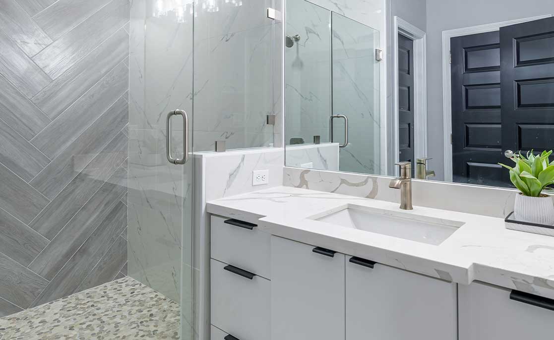 A small functionalist bathroom featuring a glass shower door and a sleek marble countertop.