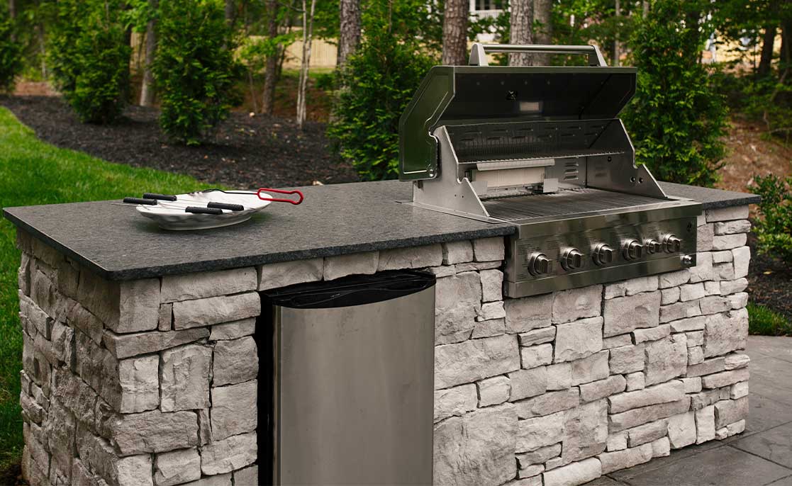 A stone countertop with a grill, showcasing outdoor living ideas for transforming Texas backyards.
