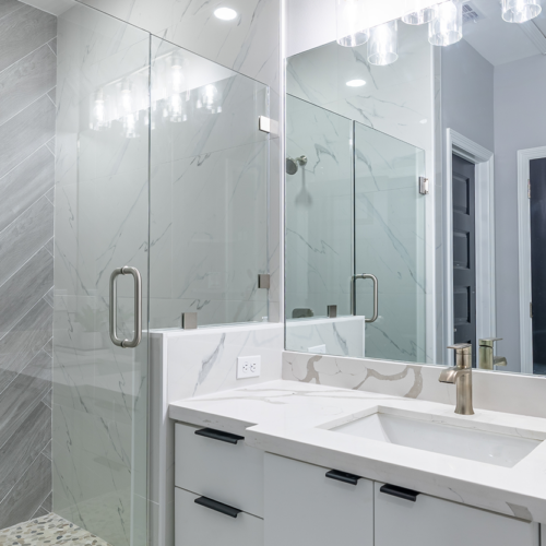 Modern bathroom design featuring glass shower and elegant marble countertops.