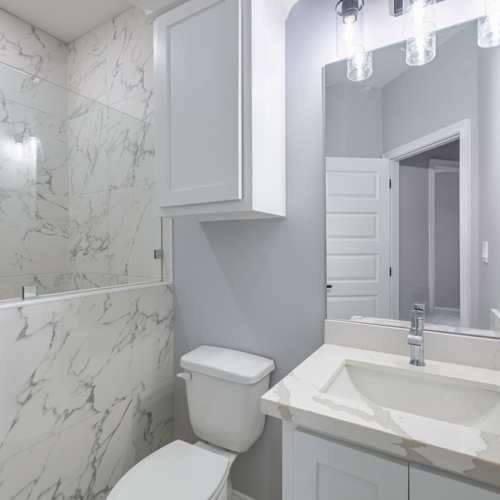 Modern bathroom with marble tiles, shower, and a stylish sink.