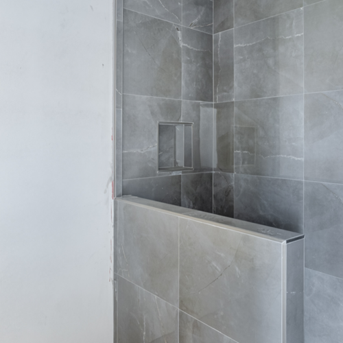 Modern shower with sleek gray tiles and minimalist design.